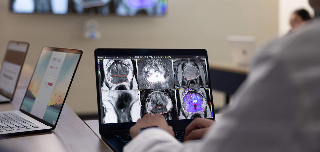 Una persona repasa resultados médicos en un MacBook. Al fondo hay otros dos dispositivos MacBook.