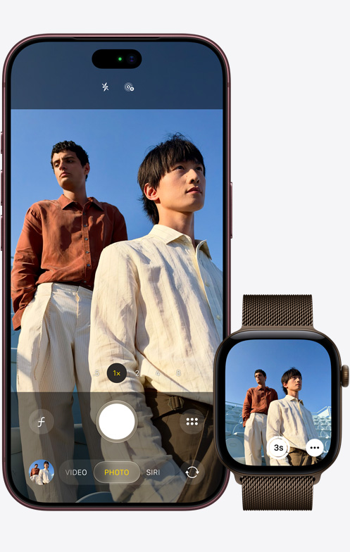 iPhone 18 Pro, front exterior, camera in use to capture two men with a blue sky in the background, next to Apple Watch Ultra 3 with Camera Remote app open